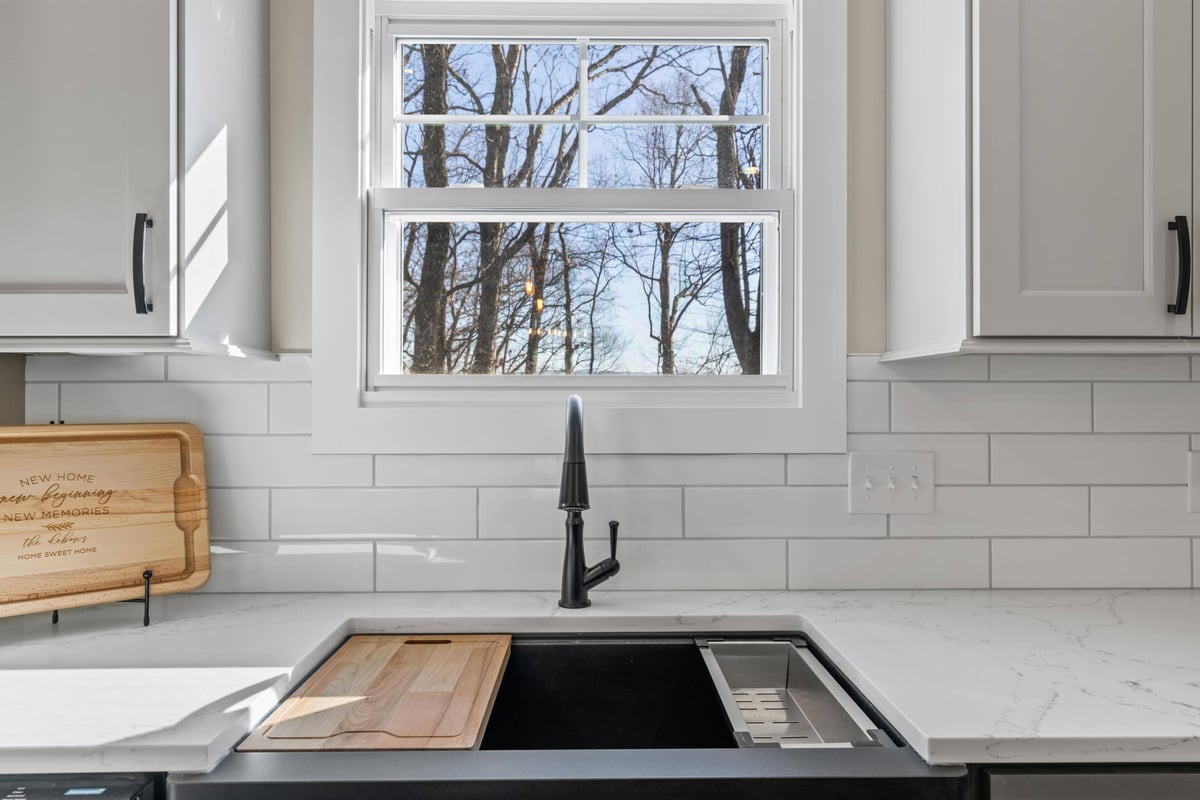 Kitchen sink with a modern black faucet and a view of the backyard through a large window in a custom home in Knoxville, TN by Debuty Builders, Inc.