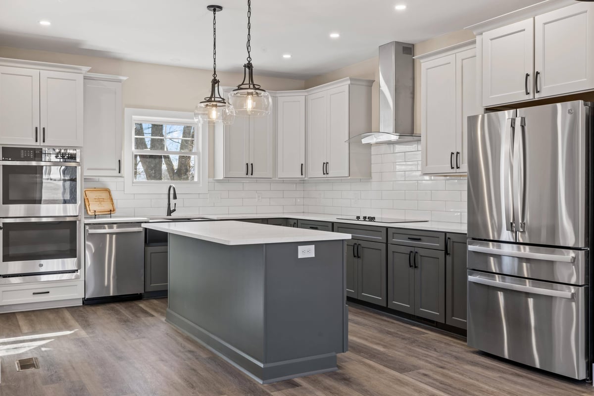 Modern kitchen in a custom home in Knoxville, TN by Debuty Builders, Inc., with white cabinets, stainless steel appliances, and a center island