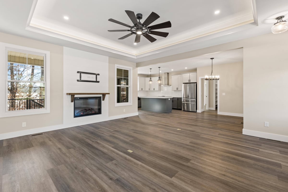 Open-concept living room and kitchen in a custom home in Knoxville, TN by Debuty Builders, Inc., with a modern fireplace and island