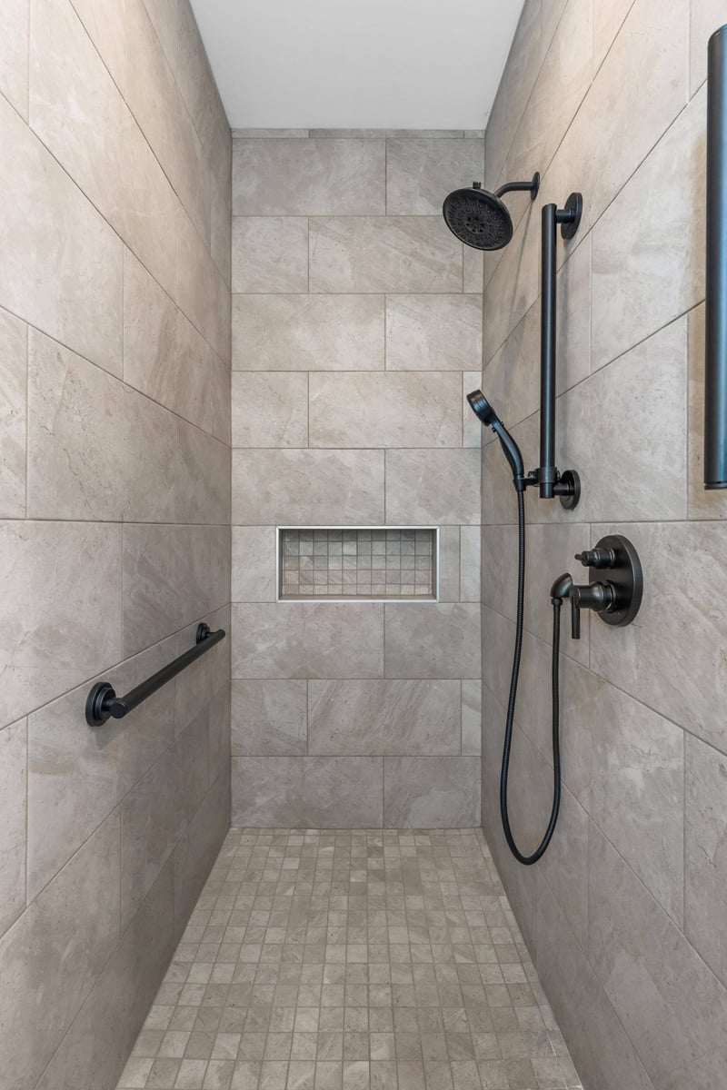 Walk-in shower with sleek tile and black fixtures in a custom home in Knoxville, TN by Debuty Builders, Inc.