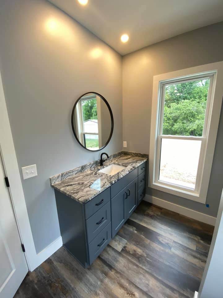 Bathroom vanity with granite countertop and round mirror in custom home by Debuty Builders, Knoxville, TN