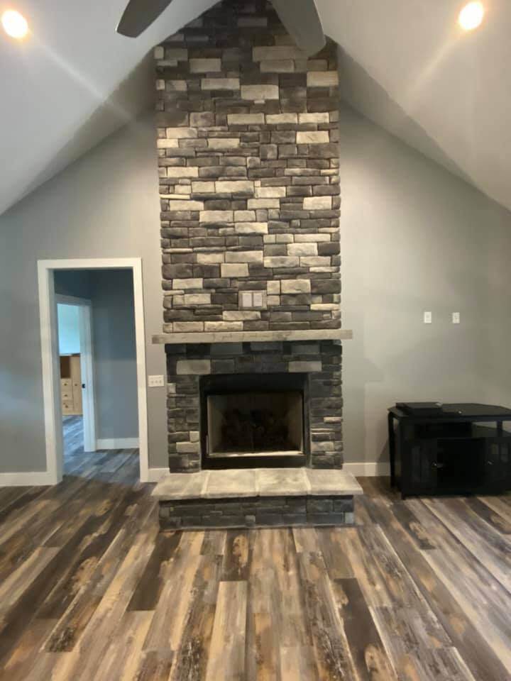 Living room with stone fireplace and wood floors in custom home by Debuty Builders, Knoxville, TN