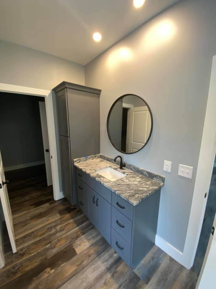 Modern bathroom vanity with granite countertop and round mirror in Debuty Builders custom home, Knoxville, TN