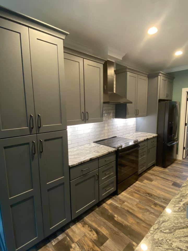 Sleek kitchen featuring granite countertops and gray cabinetry in Knoxville custom home by Debuty Builders