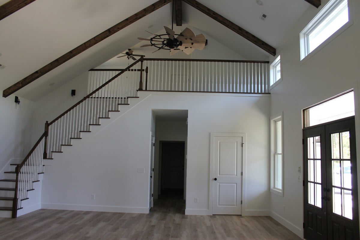 Custom home living room with vaulted ceiling, exposed beams, and a staircase by Debuty Builders, Knoxville, TN