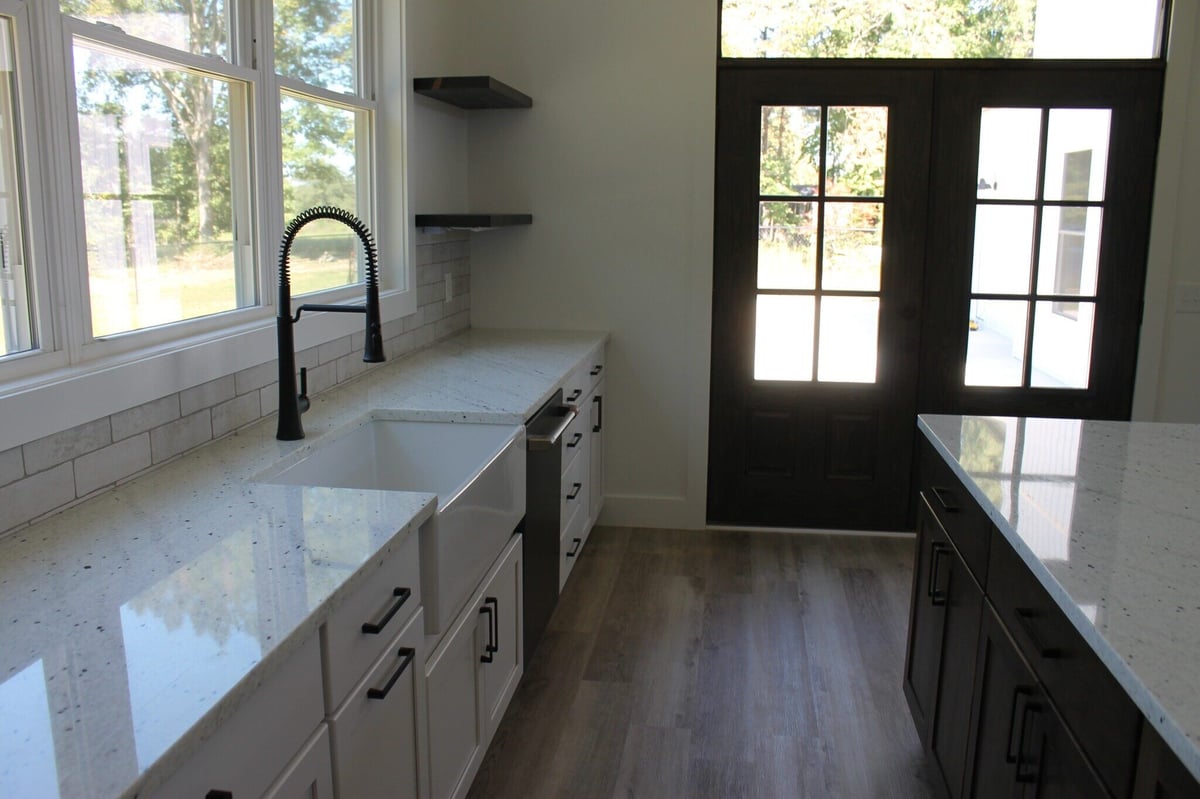 Kitchen featuring white cabinets, farmhouse sink, and large windows by Debuty Builders, Knoxville, TN