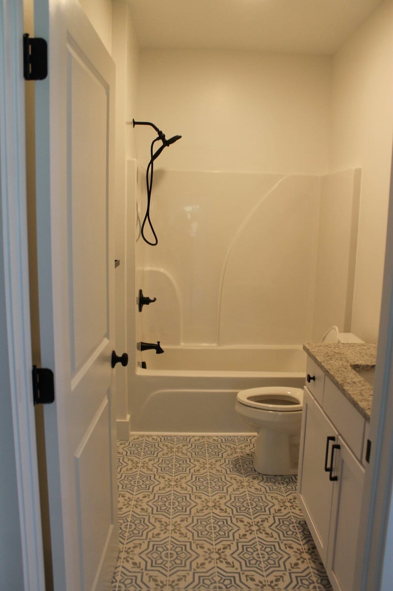Modern bathroom with patterned tile floor and white tub by Debuty Builders, Knoxville, TN