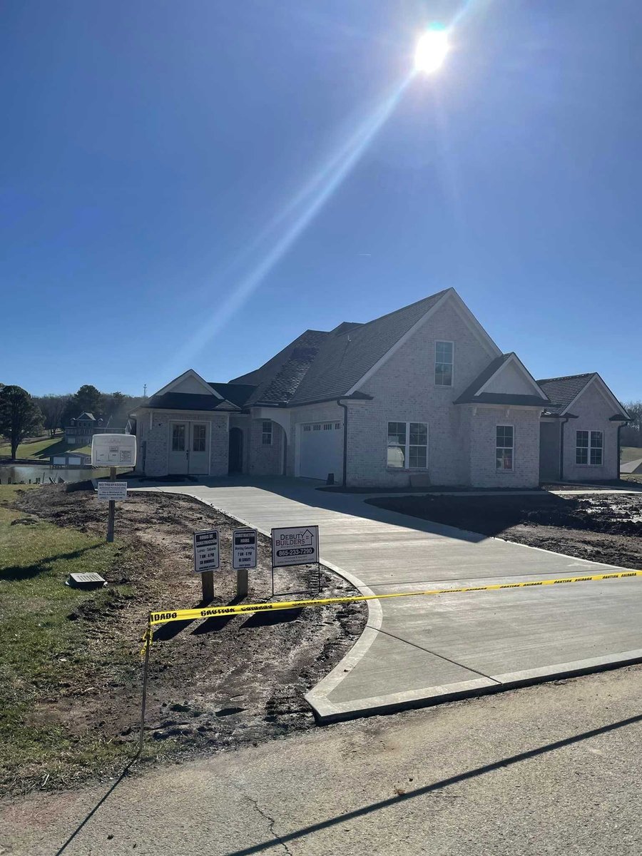 Completed custom home with freshly poured driveway and Debuty Builders signage in Knoxville, TN
