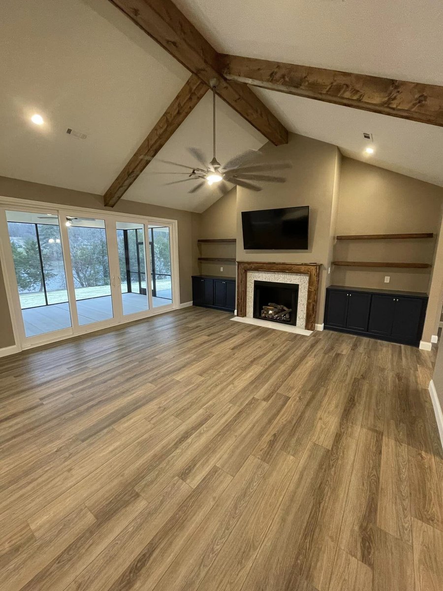Open-concept living room with wood beams and large windows in Knoxville, TN by Debuty Builders