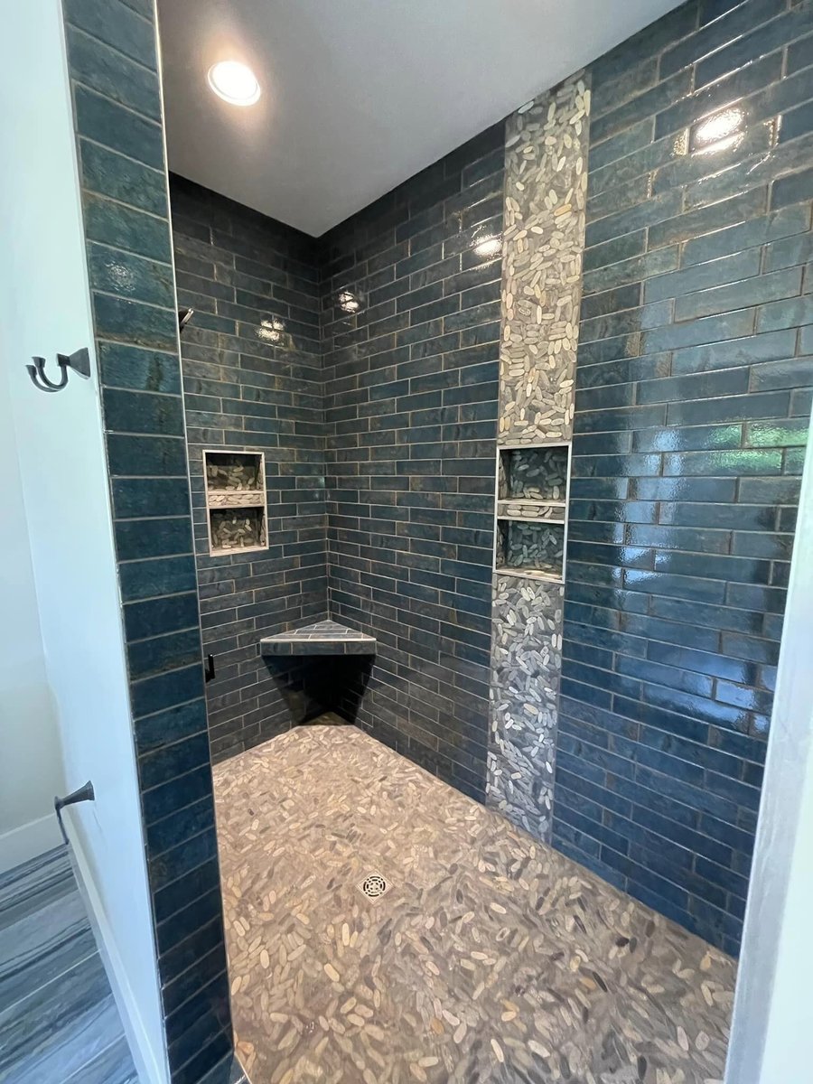 Custom shower with dark tile and pebble accents in a bathroom by Debuty Builders, Knoxville, TN