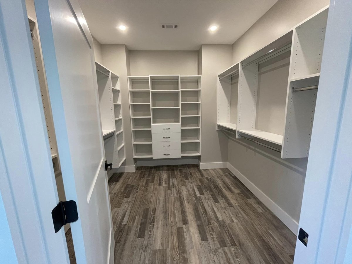 Spacious custom walk-in closet with white shelving installed by Debuty Builders in Knoxville, TN