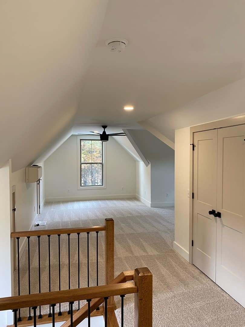 Carpeted attic space with ceiling fan in a custom home by Debuty Builders, Knoxville, TN
