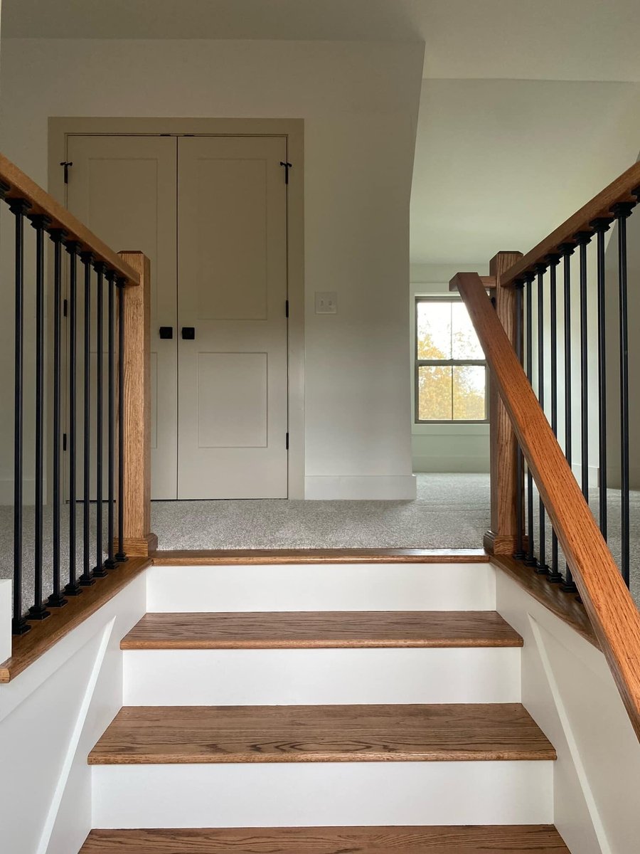 Hardwood staircase with black iron railing leading to upper floor in a custom home by Debuty Builders in Knoxville, TN