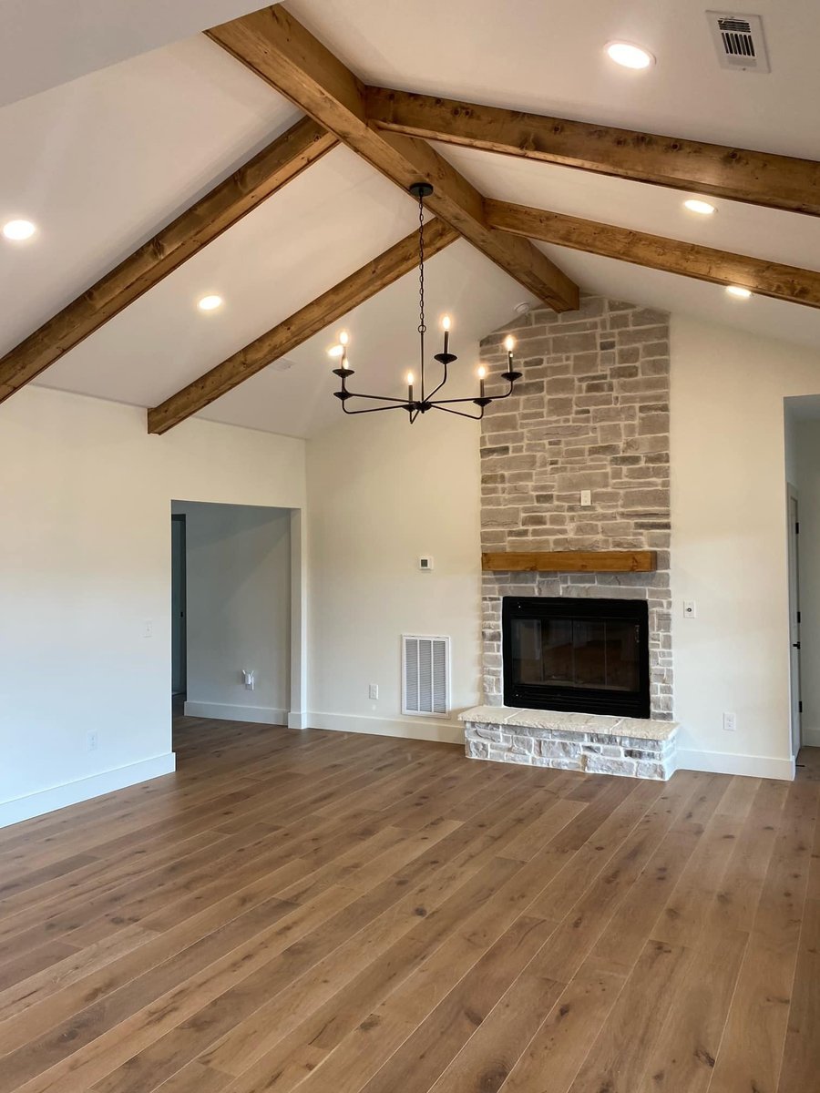 Living room with vaulted ceilings, exposed wooden beams, and stone fireplace in a custom home by Debuty Builders, Knoxville, TN