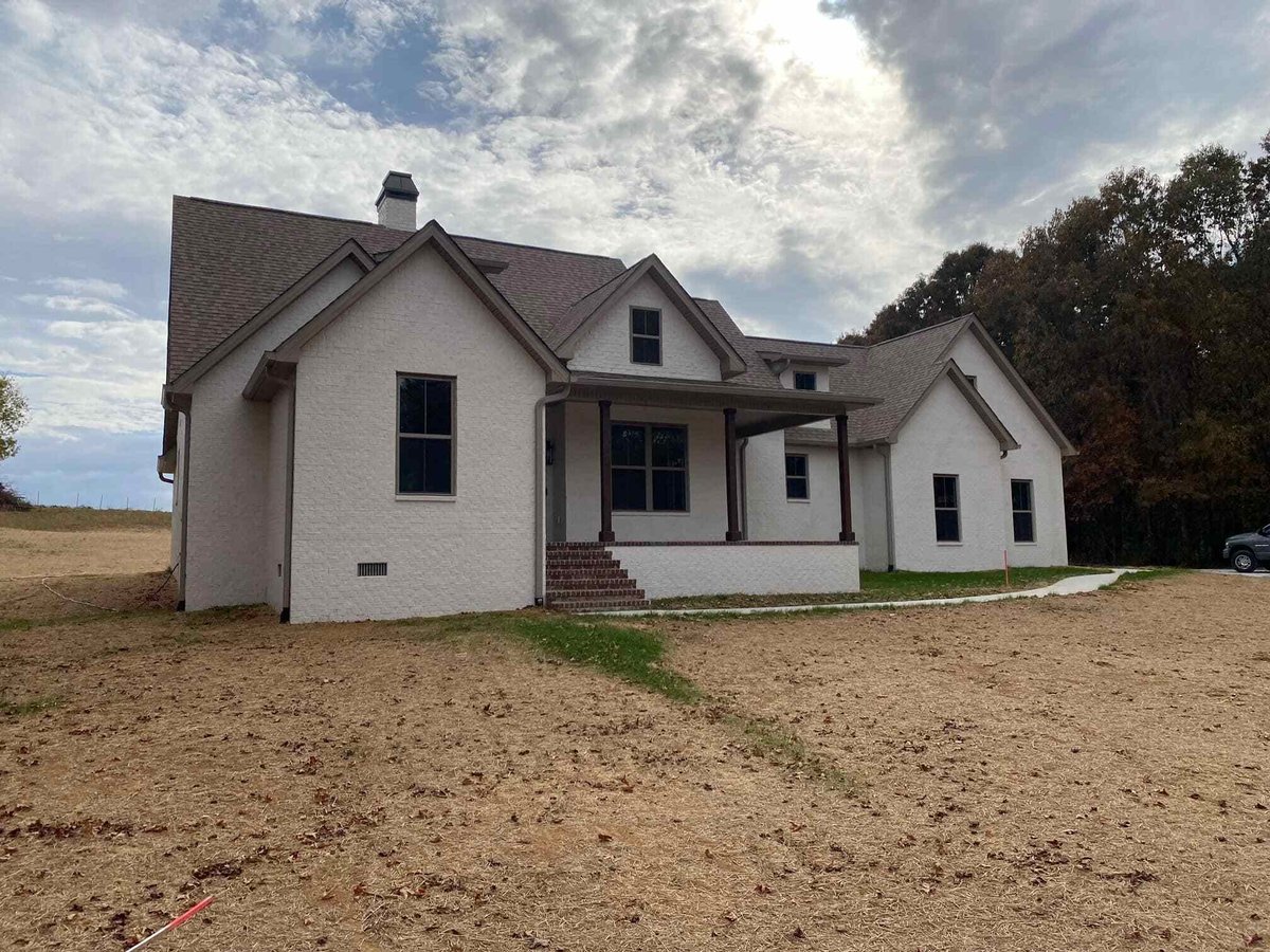 White brick custom home with front porch and dark window frames by Debuty Builders, Knoxville, TN