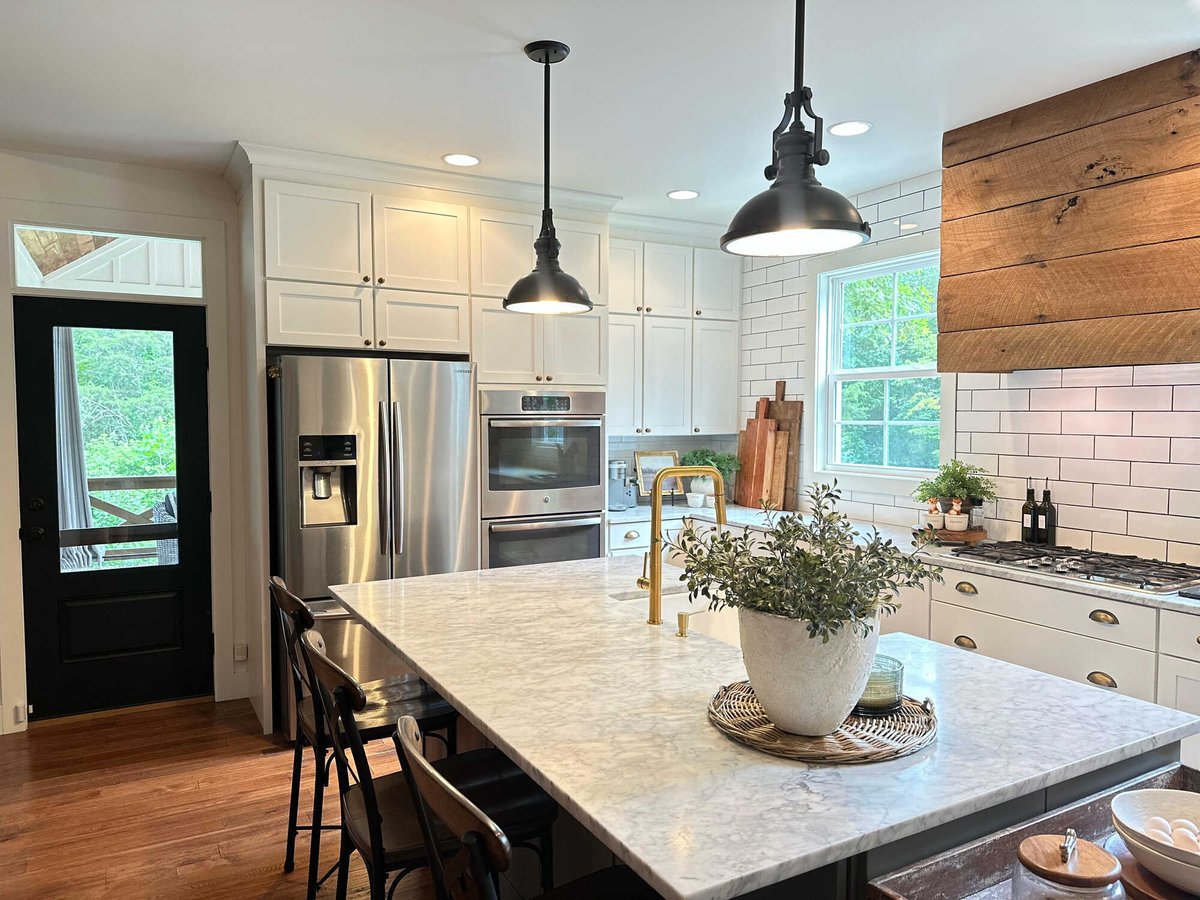 Custom kitchen featuring a marble island with seating and a farmhouse sink by Debuty Builders, Knoxville, TN