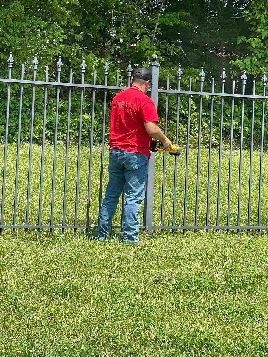 Debuty Builders employee in a red shirt fixing a metal fence for a custom home in Knoxville, Tennessee