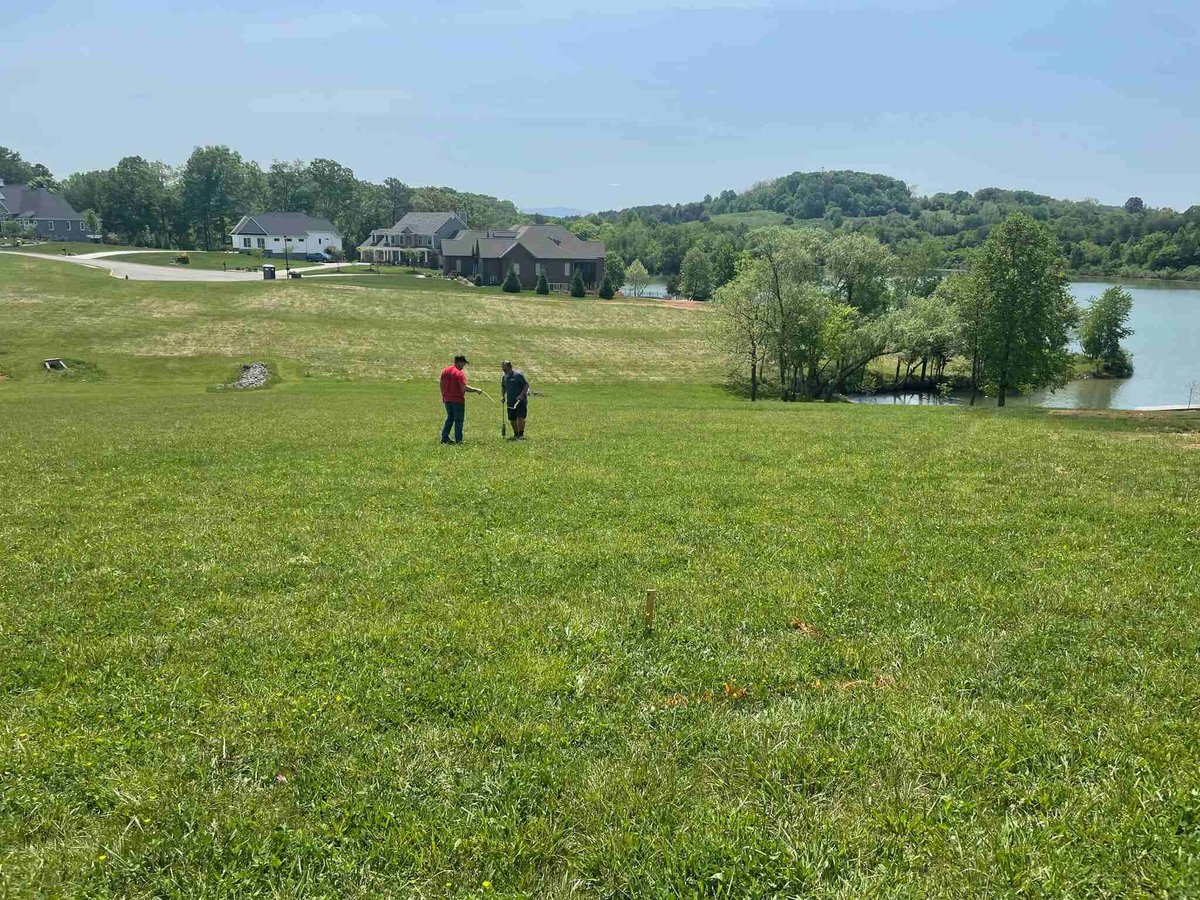 Debuty Builders staff discussing project plans on a large green plot overlooking a lake in Knoxville, TN