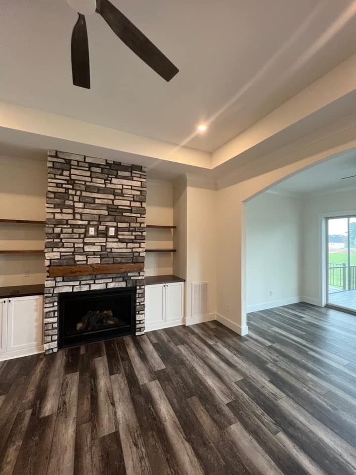 Living room with stone fireplace and wood flooring in a custom home by Debuty Builders, Knoxville, TN