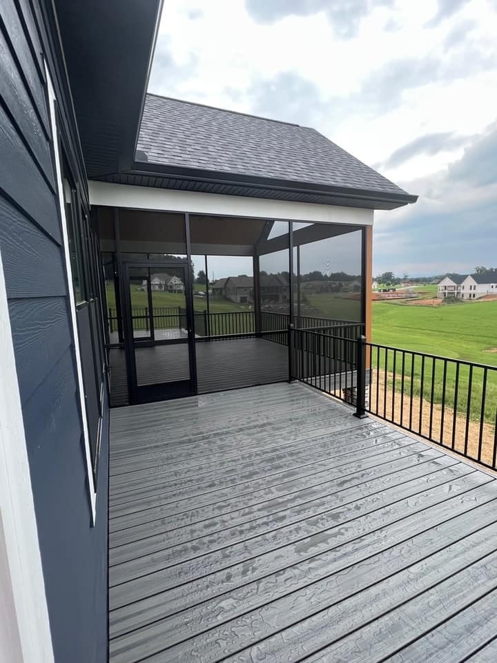 Screened-in back porch with wooden ceiling and black railing overlooking green landscape by Debuty Builders, Knoxville, TN