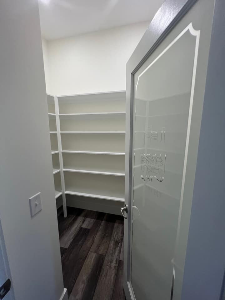 Walk-in pantry with built-in shelving and a frosted glass door in a custom home by Debuty Builders, Knoxville, TN