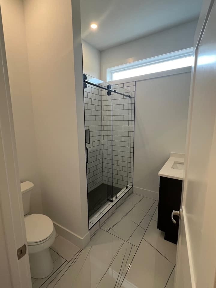 White subway-tiled shower with black frame and glass doors in a custom home by Debuty Builders, Knoxville, TN