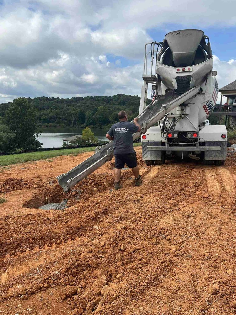 Worker pouring concrete foundation at a custom home site by Debuty Builders, Knoxville, TN