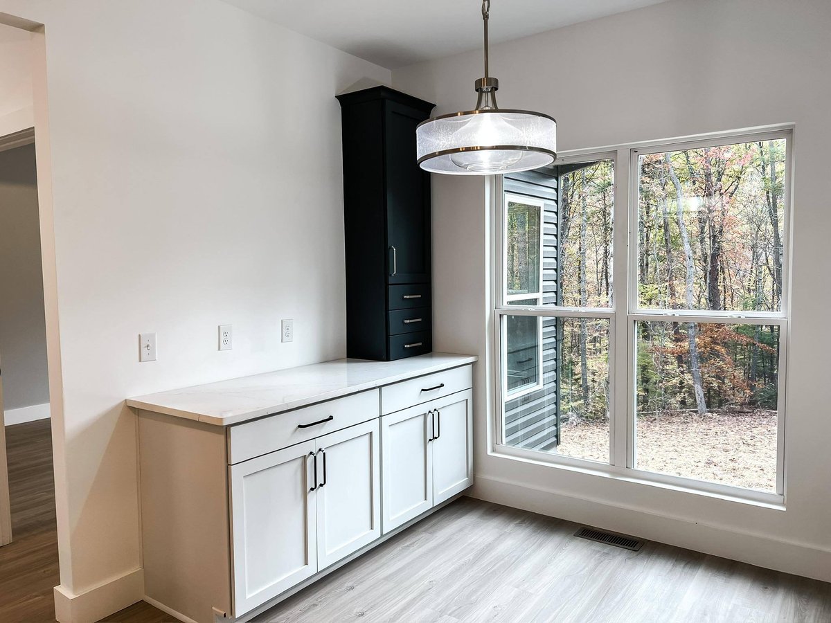 Breakfast nook with white cabinetry and large windows overlooking a wooded area in a custom home in Knoxville, TN by Debuty Builders, Inc