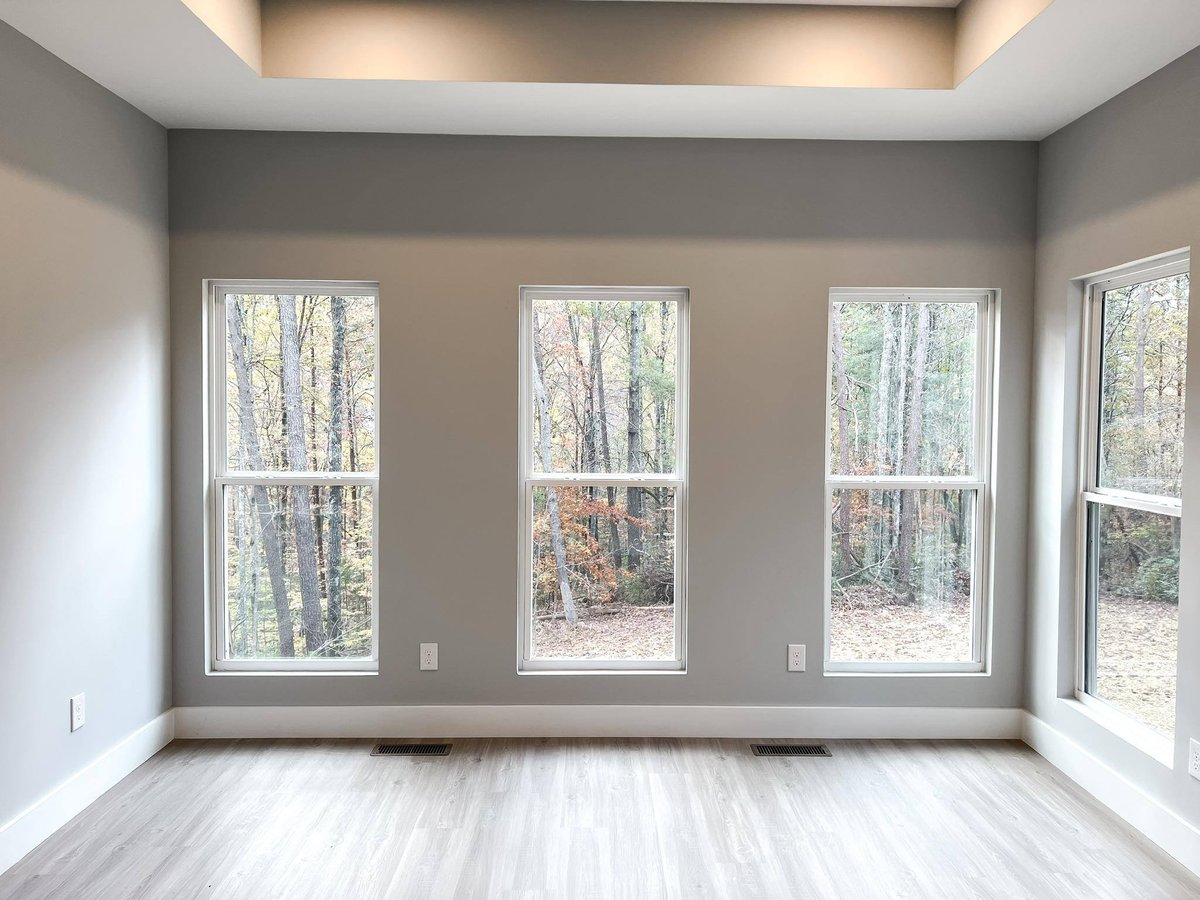 Bright room with four large windows showcasing scenic wooded views in a custom home in Knoxville, TN by Debuty Builders, Inc.