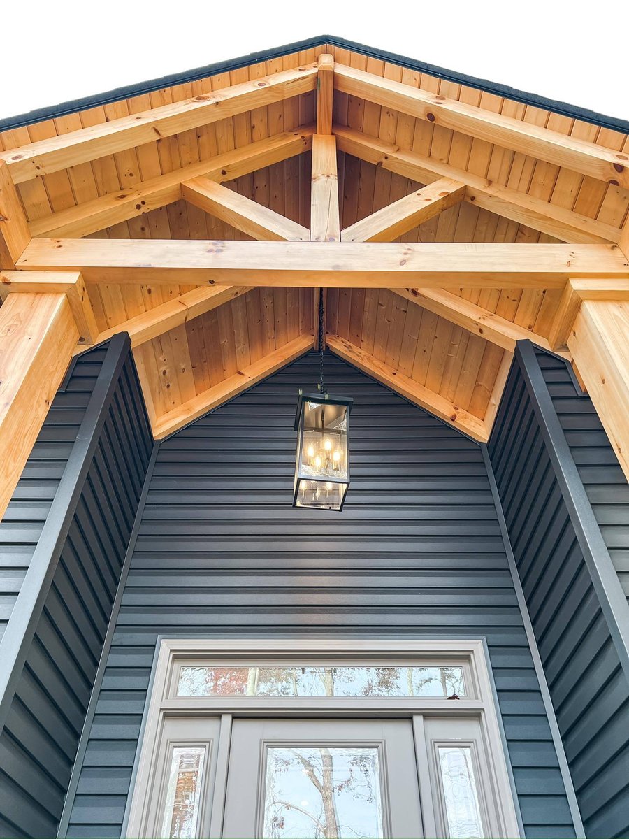 Close-up of a covered entryway with exposed timber beams and a modern hanging light in a custom home in Knoxville, TN by Debuty Builders, Inc.