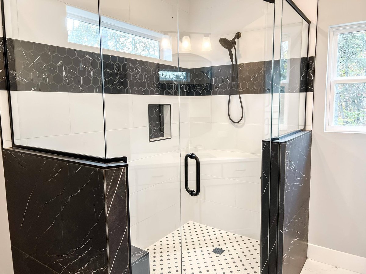 Detailed view of the walk-in shower with black-and-white tiling and frameless glass doors in a custom home in Knoxville, TN by Debuty Builders, Inc.