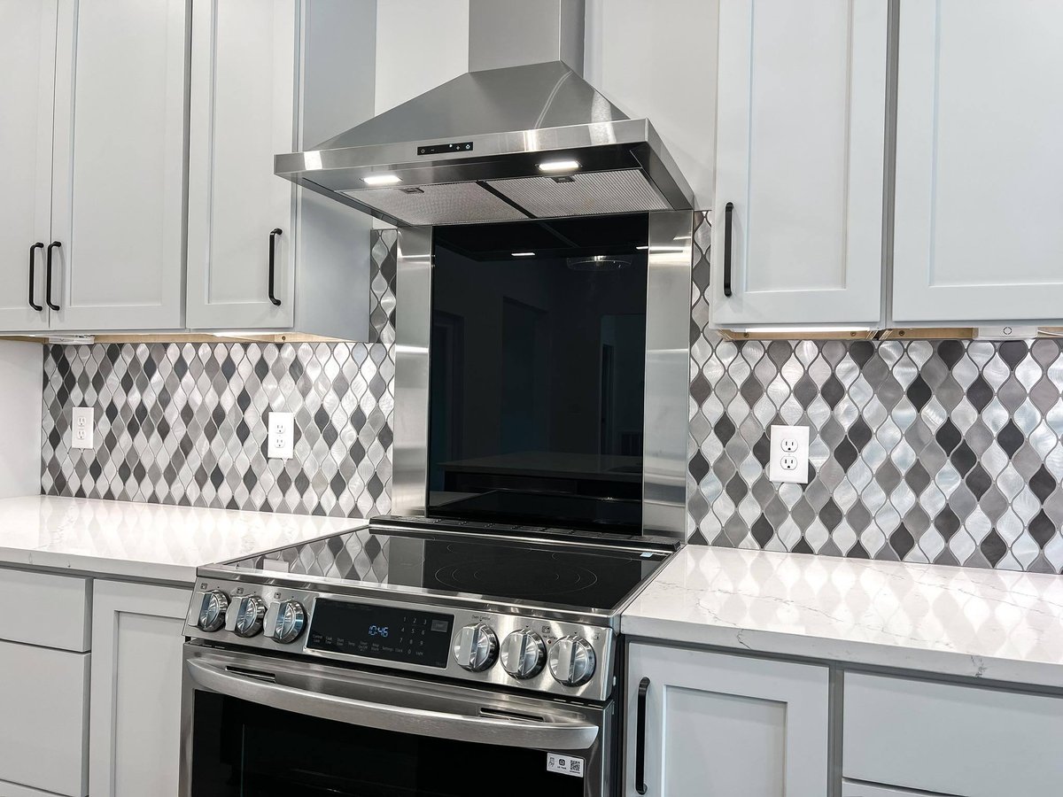 Kitchen stove area with white cabinetry and black and white backsplash in a custom home in Knoxville, TN by Debuty Builders, Inc.