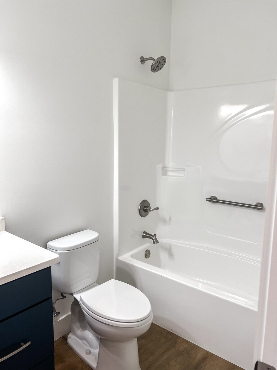 Bathroom with tub and shower combo in a custom home by Debuty Builders, Inc. in Maryville, TN, featuring a sleek white design and modern fixtures