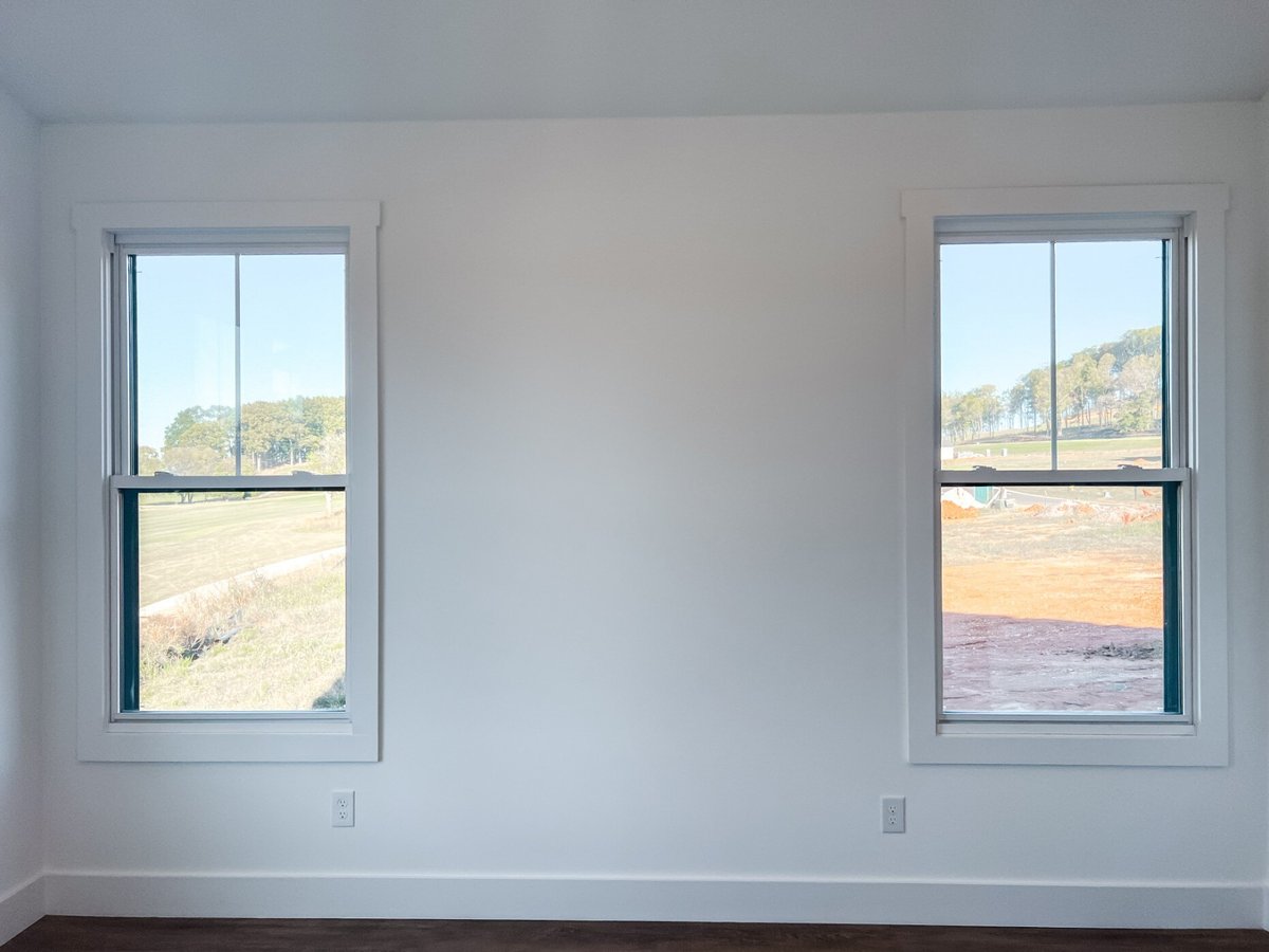 Bedroom in a custom home by Debuty Builders, Inc. in Maryville, TN, showcasing dual windows with a view of the outdoors, providing ample natural light against a clean white wall