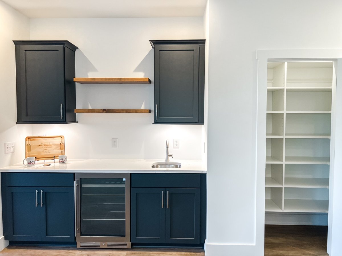 Butlers pantry in a custom home by Debuty Builders, Inc. in Maryville, TN, with dark cabinets, floating wooden shelves, and a compact wine fridge