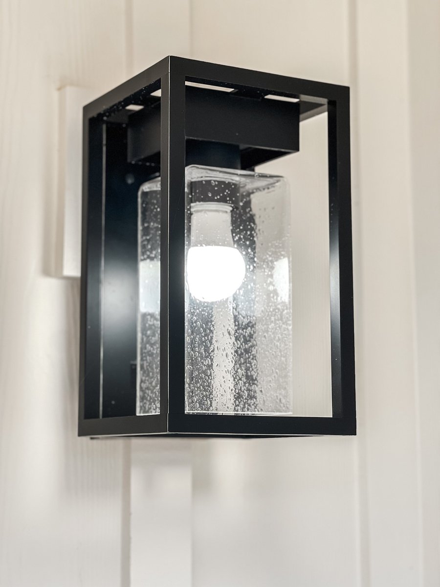 Close-up of a modern black metal and glass wall light fixture in a custom home by Debuty Builders, Inc. in Maryville, TN