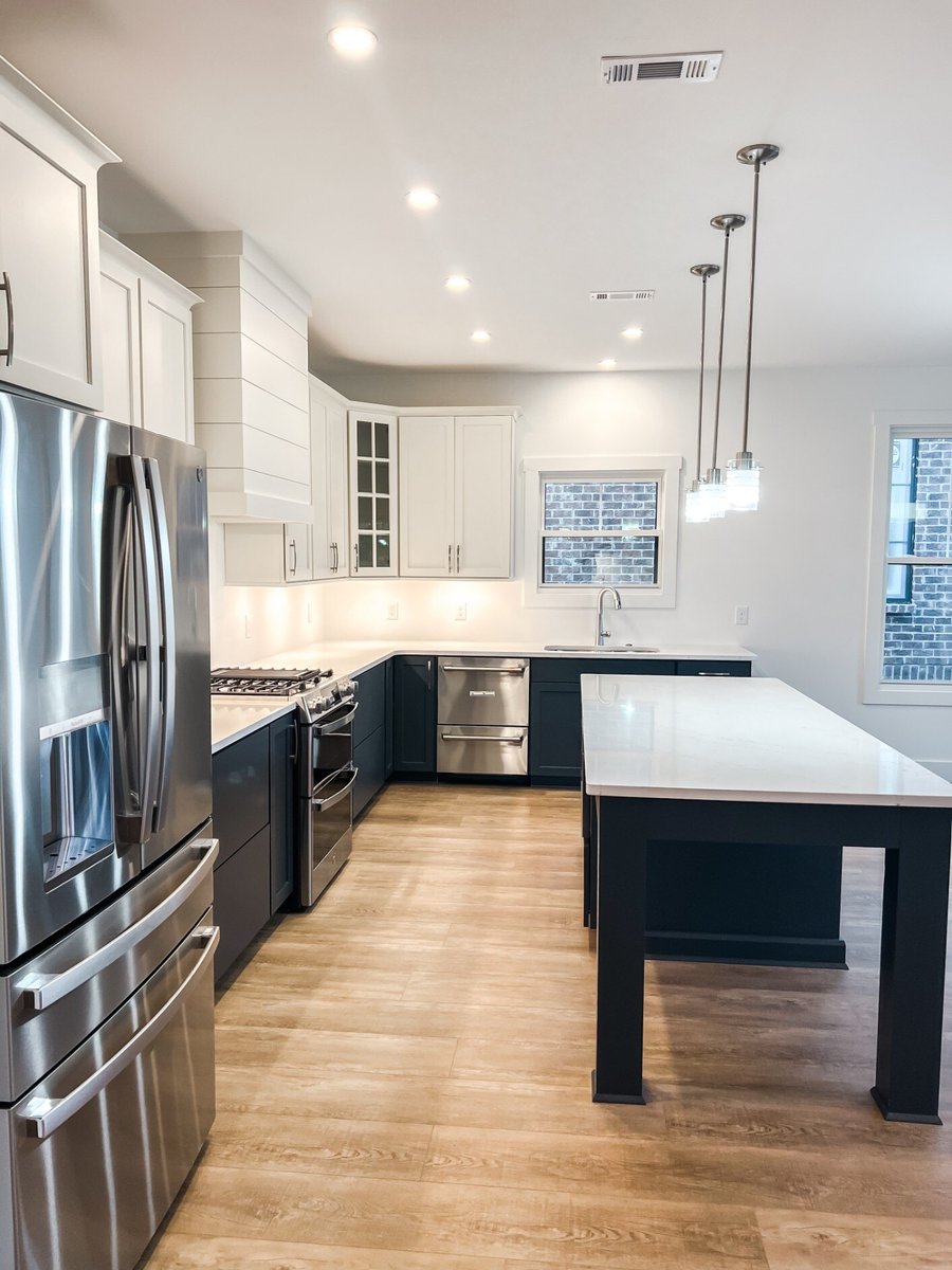 Elegant kitchen in a custom home by Debuty Builders, Inc. in Maryville, TN, featuring a large island, stainless steel appliances, and white and dark cabinetry