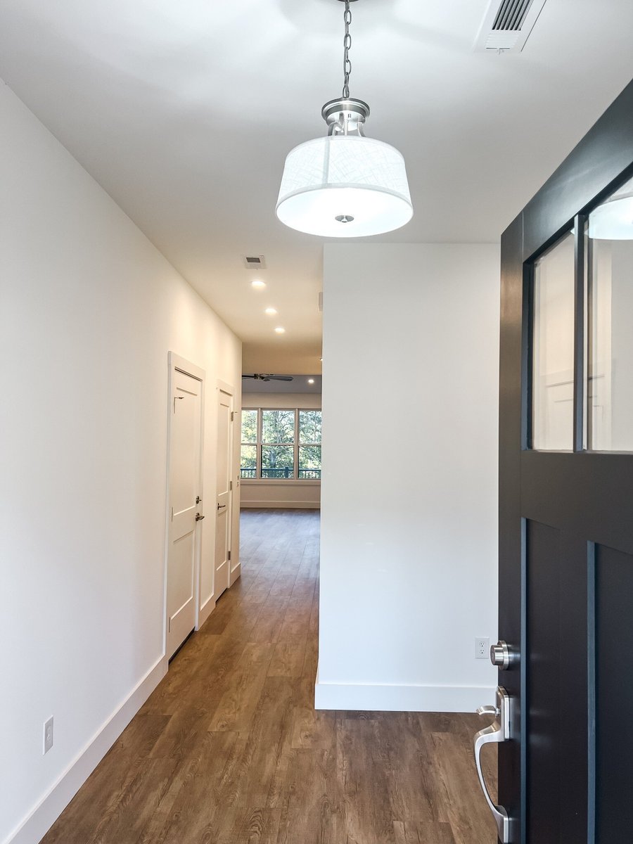 Entryway in a custom home by Debuty Builders, Inc. in Maryville, TN, with a view down the hallway towards the living room, featuring a modern light fixture