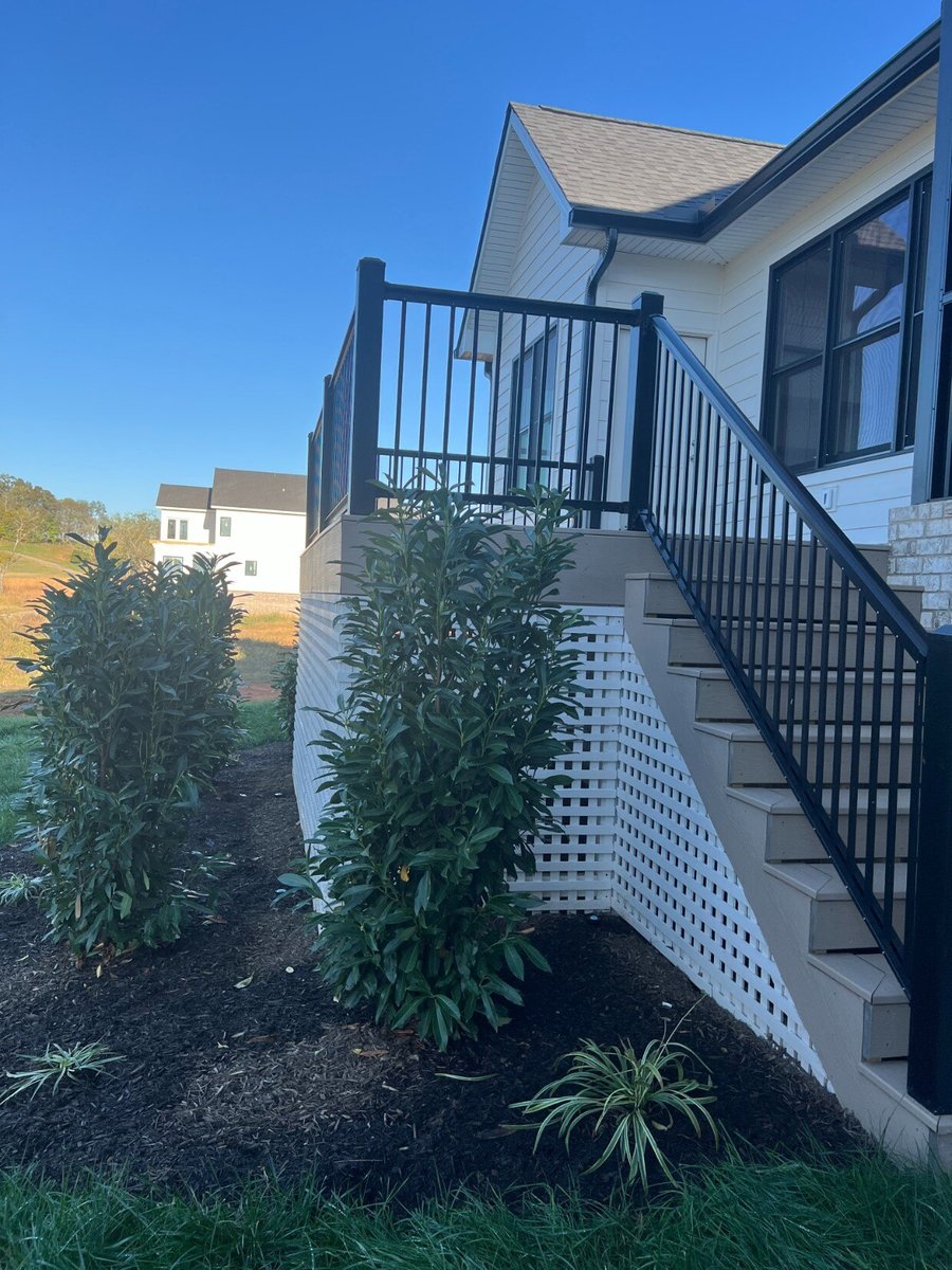 Exterior stairway leading to a raised deck area of a custom home by Debuty Builders, Inc. in Maryville, TN, with newly planted landscaping and black railing