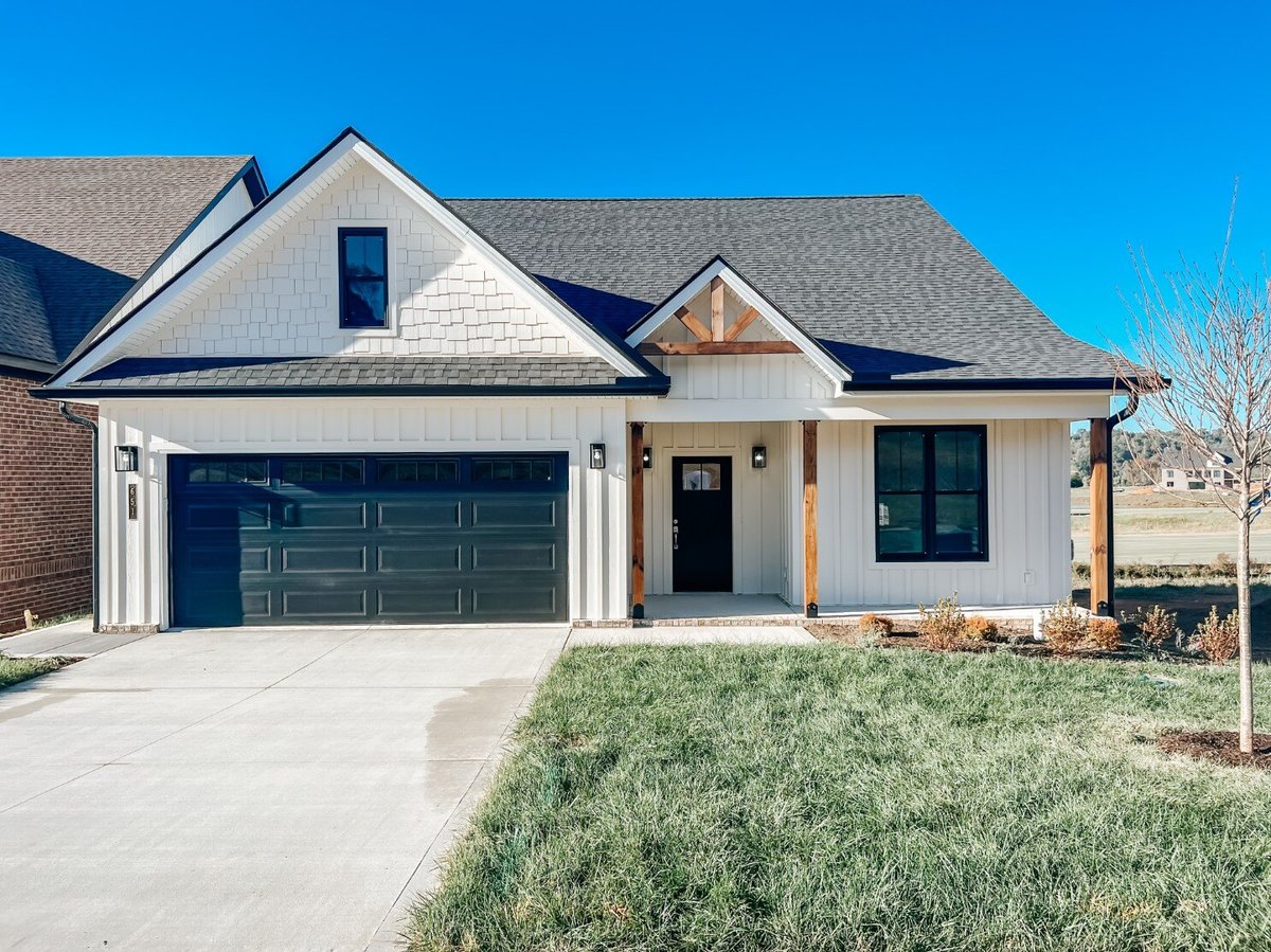 Front exterior of a custom home by Debuty Builders, Inc. in Maryville, TN, showcasing a craftsman-style facade with a covered porch, black garage doors, and wood accents