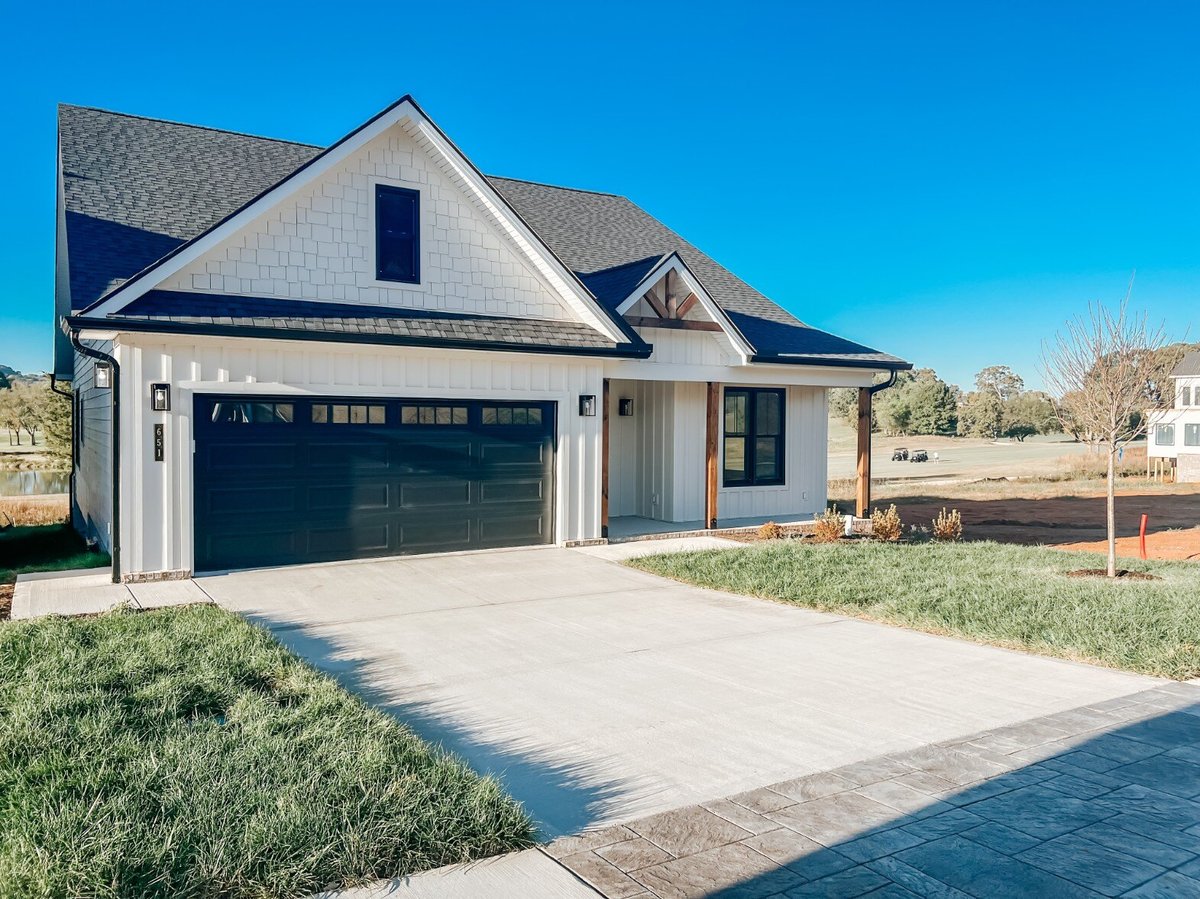 Front exterior view of a custom home by Debuty Builders, Inc. in Maryville, TN, with a welcoming driveway, black garage doors, and craftsman-style details on the porch