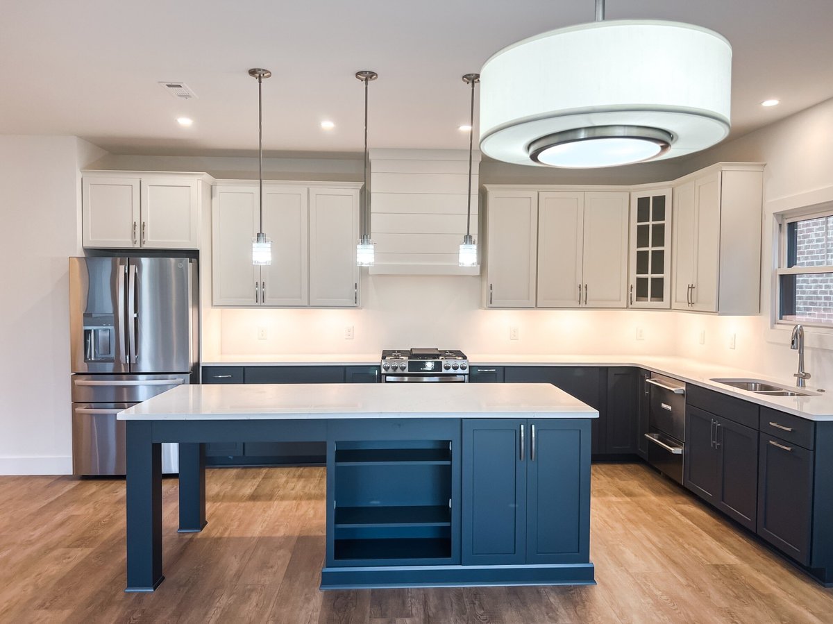 Modern kitchen design by Debuty Builders, Inc. in Maryville, TN, with pendant lighting, a large central island, and stainless steel appliances