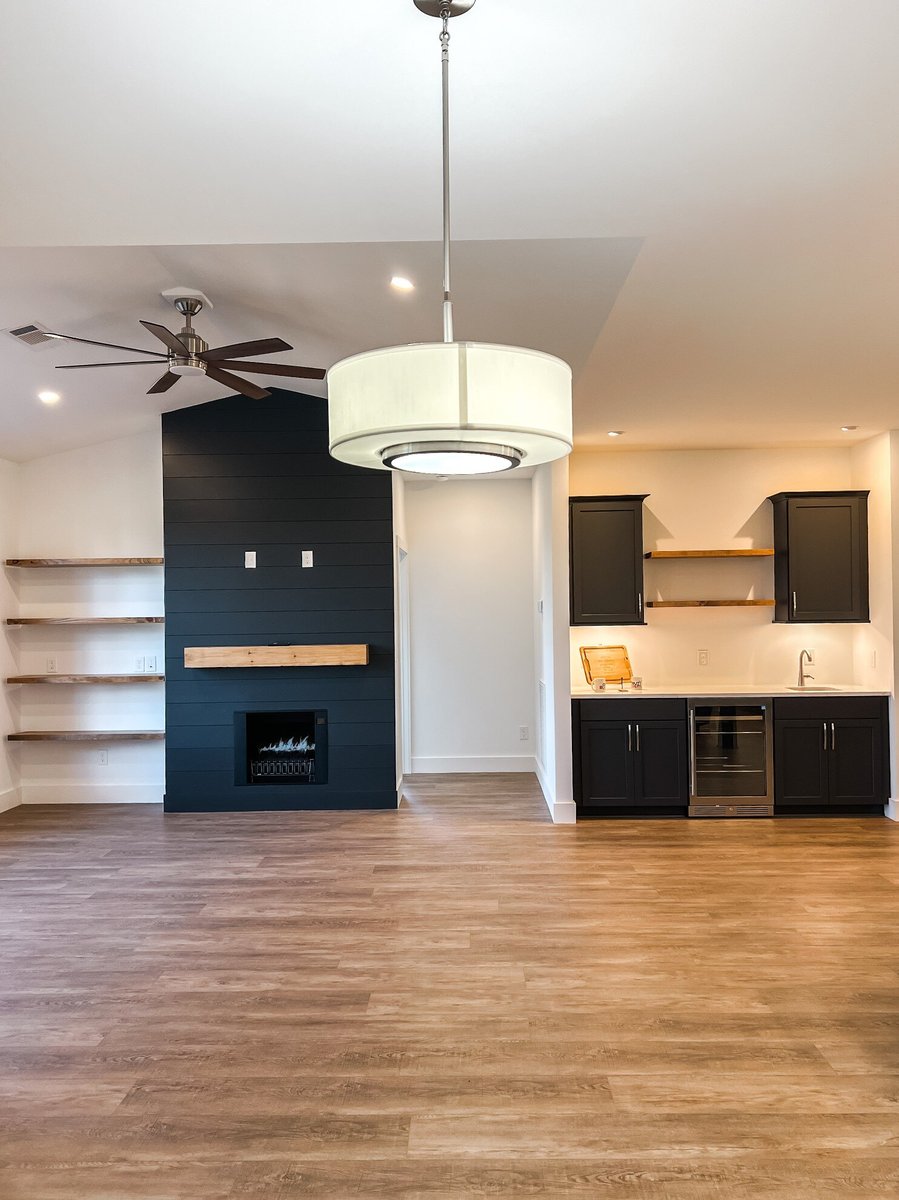 Open living area in a custom home by Debuty Builders, Inc. in Maryville, TN, showcasing a fireplace with a shiplap accent wall, custom shelving, and a sleek, modern ceiling fan