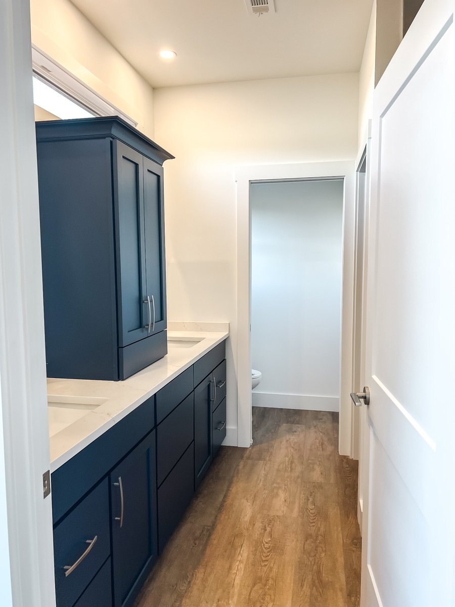 Primary bathroom of a custom home by Debuty Builders, Inc. in Maryville, TN, featuring a navy-blue double vanity with white countertops and modern hardware.