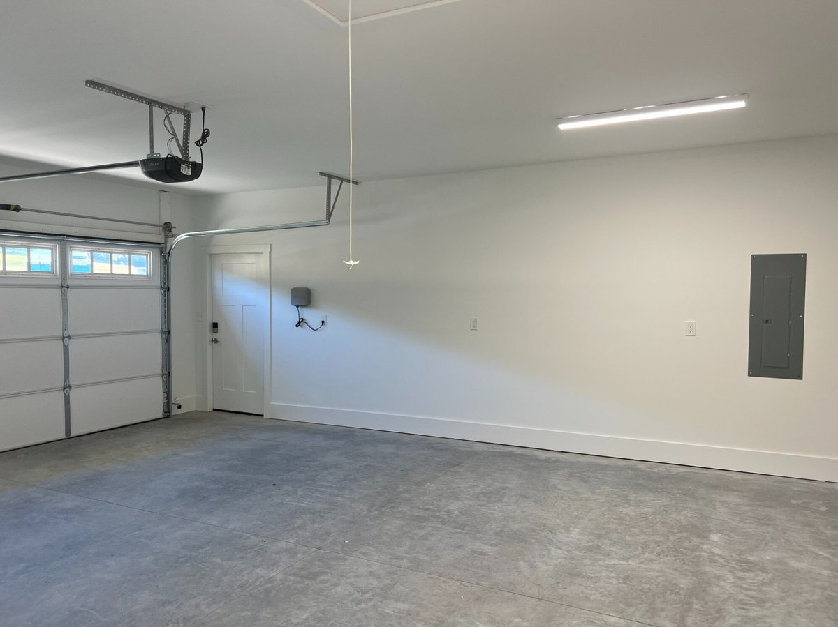 Spacious garage interior of a custom home by Debuty Builders, Inc. in Maryville, TN, featuring a clean white finish, overhead lighting, and a garage door