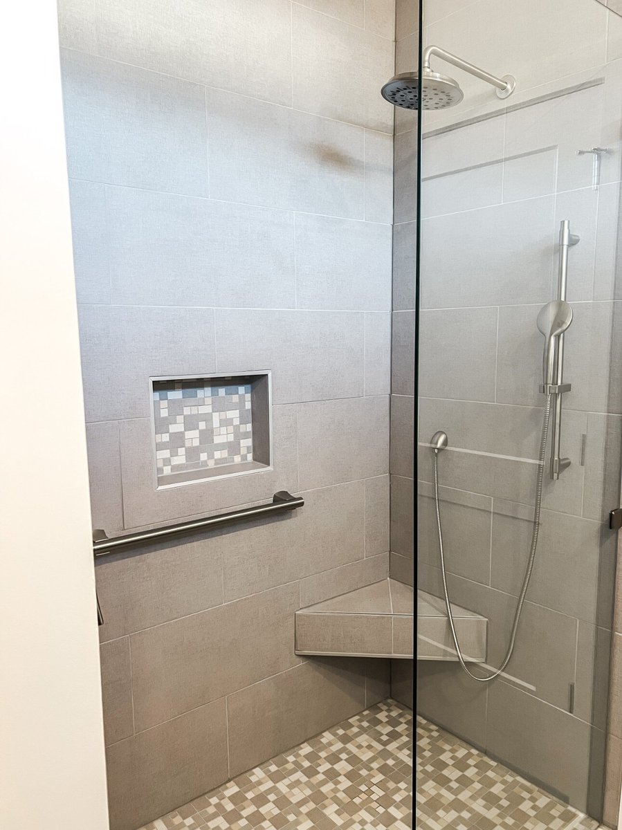 Walk-in shower in a custom home by Debuty Builders, Inc. in Maryville, TN, with light gray tile, a built-in niche, and a corner seat for modern functionality