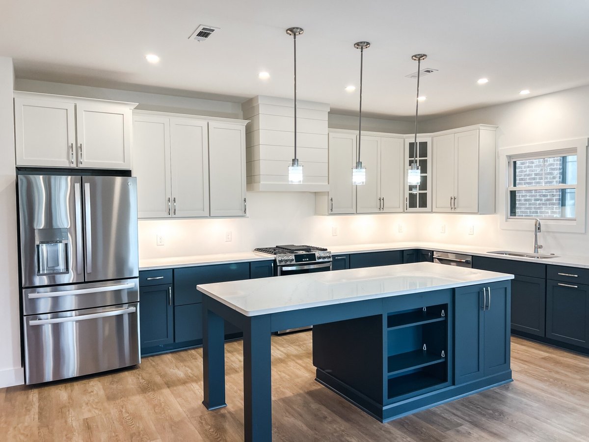 Wide-angle view of a modern kitchen in a custom home by Debuty Builders, Inc. in Maryville, TN, with a spacious island, pendant lighting, and white cabinetry